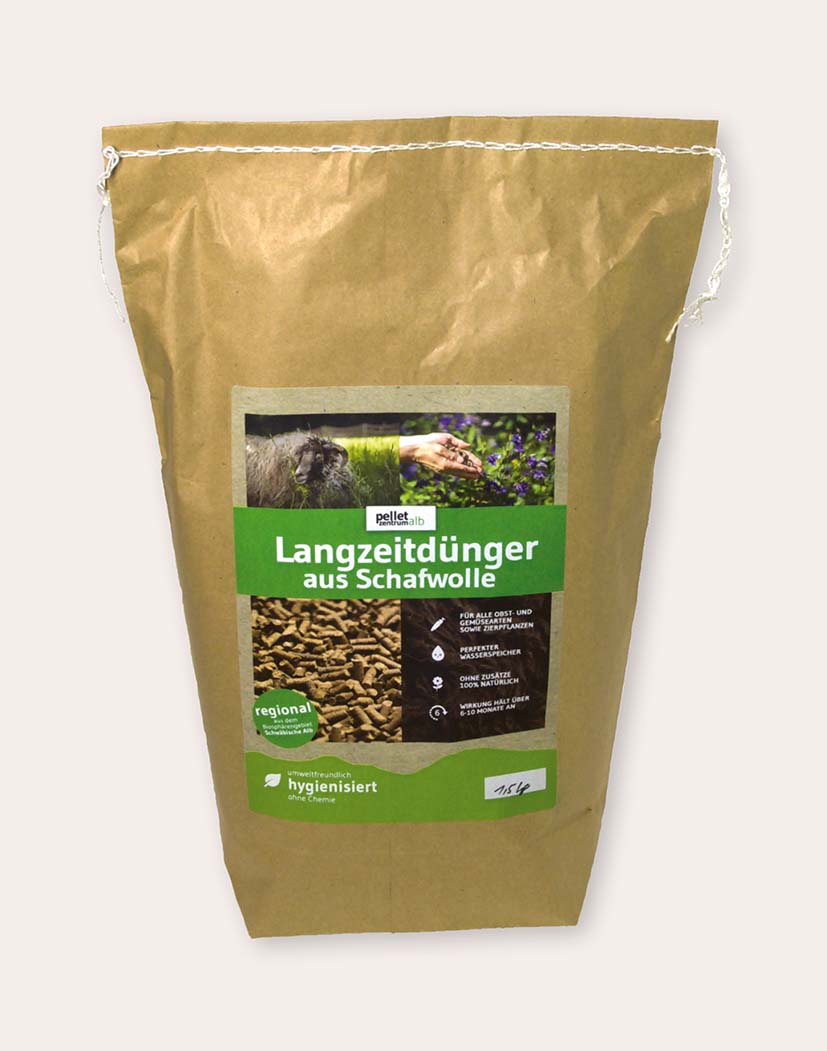 Brauner Papiersack mit grünem Etikett: Langzeitdünger aus Schafwolle. Auf dem Etikett Fotos von Schaf, Hand mit Dünger und Pellets; Produkt in Pelletform, hygienisiert und regional.