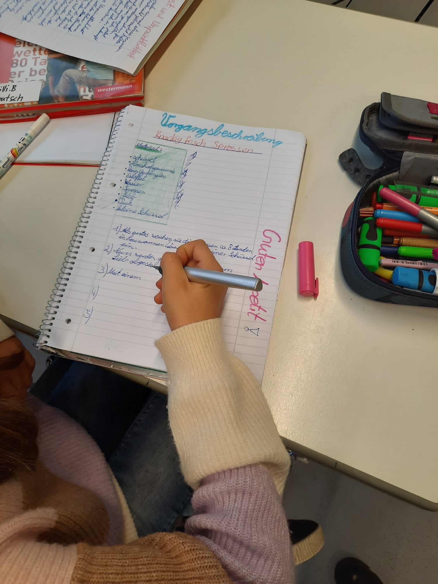 Notizbuch mit Schreibarbeiten und bunten Stiften auf einem Tisch