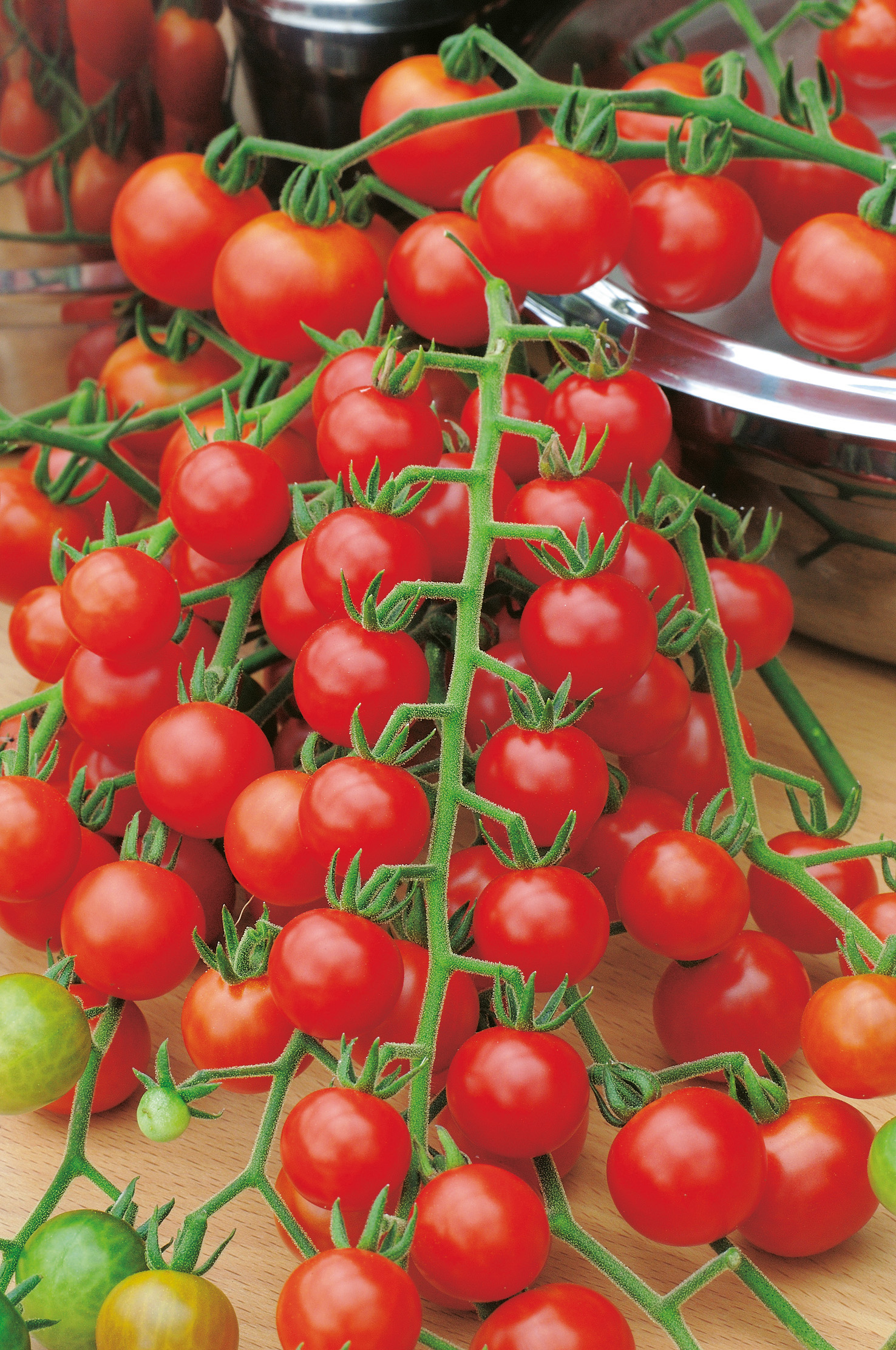 93541_Obsttomaten Freude Nahaufnahme mehrerer Rispen reifer roter Cherry-Tomaten mit grünen Stielen auf Holzbrett, glänzende saftige Früchte