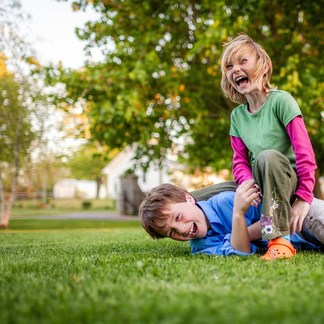 Zwei Kinder toben lachend auf einem dichten grünen Gartenrasen – Rasensamen BG Spielrasen II für pflegeleichte, schnell keimende und belastbare Spiel- und Freizeitflächen.