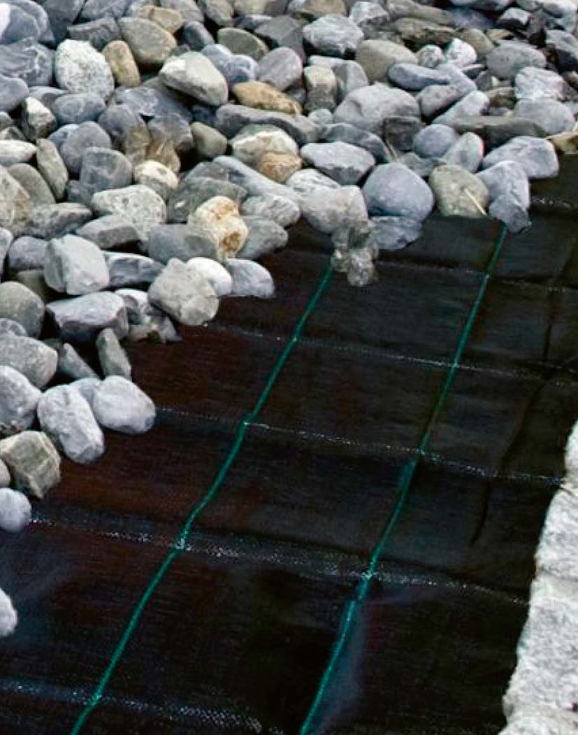 Bodenvlies/Unkrautvlies unter grauen Kiessteinen, schwarzes Geotextil mit sichtbaren grünen Rasternähten