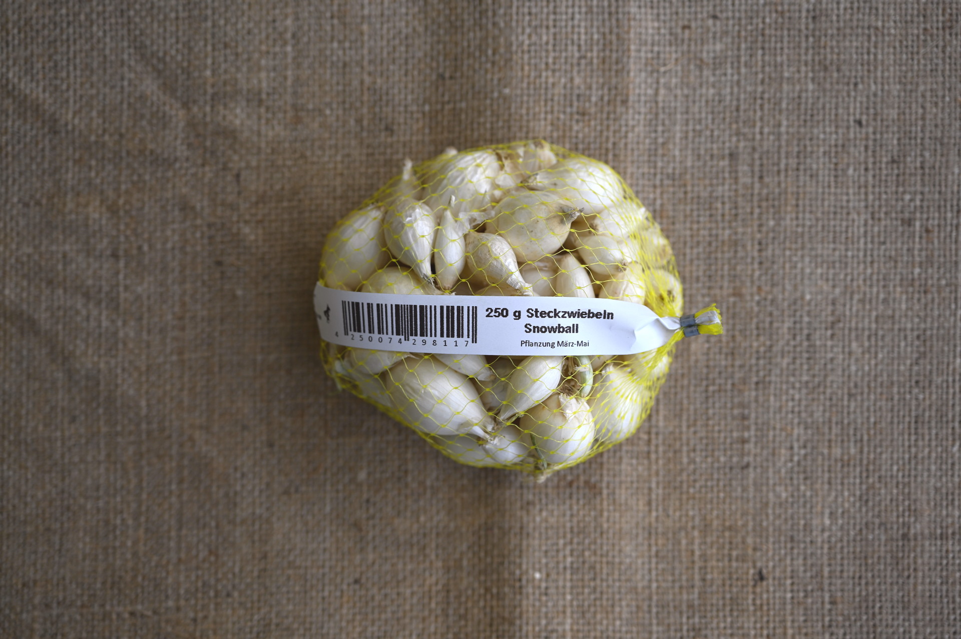 Netzbeutel mit weißen Steckzwiebeln Snowball, einer frühen schossfesten Sorte mit mild-süßem Aroma und saftigem Geschmack, ideal für den Frischverzehr.