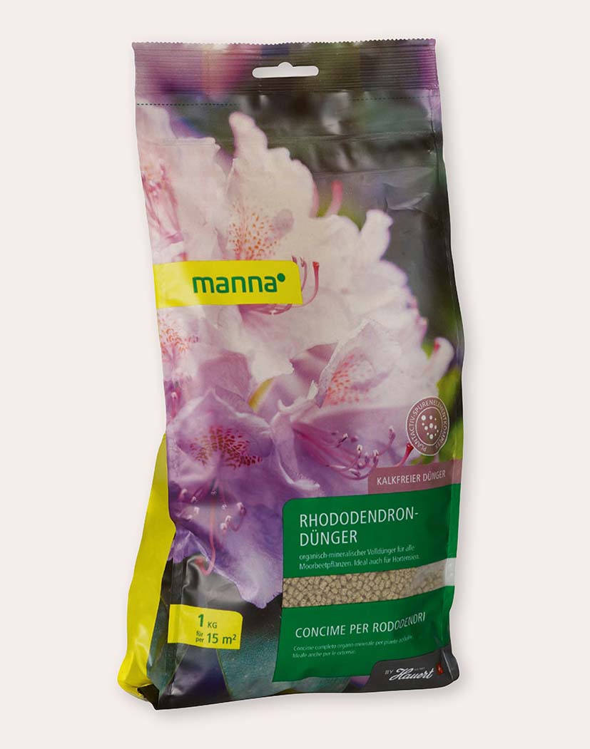 Packung 'manna' Rhododendron-Dünger 1 kg mit rosa-lila Rhododendronblüten-Motiv, grünem Produktetikett, Hinweis 'kalkfreier Dünger' und sichtbarem körnigem Granulat